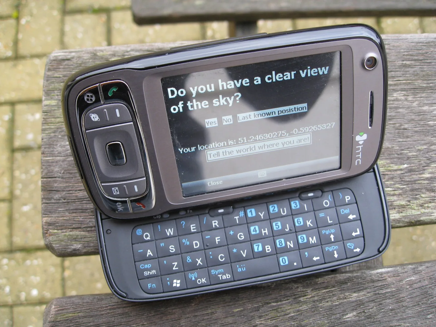 HTC TyTN II z uchylonym ekranem i wysuniętą klawiaturą, na ekranie pytanie o czysty widok na niebo przy ustalaniu pozycji GPS