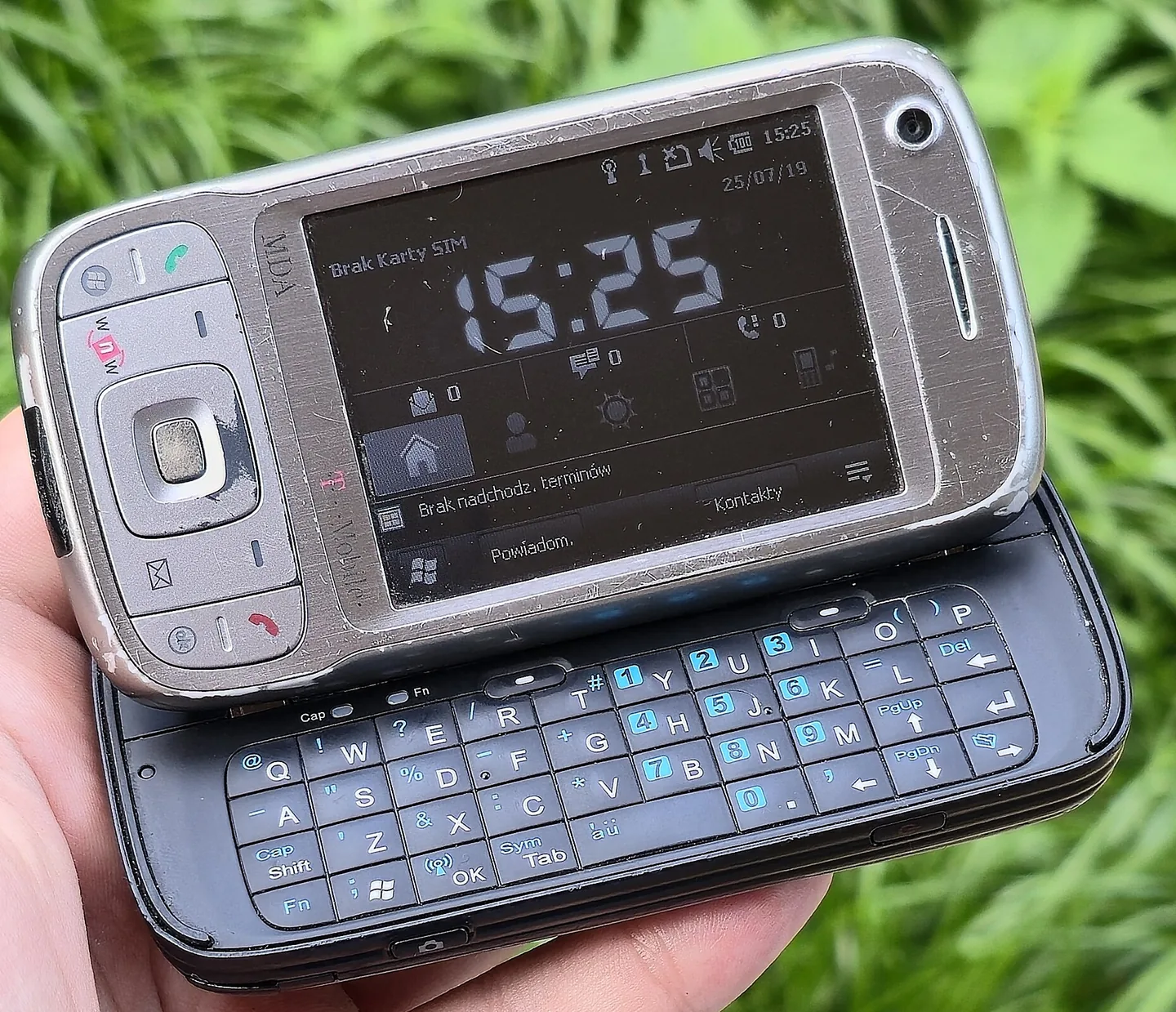 HTC TyTN II jako T-Mobile MDA Vario III trzymany w dłoni, wysunięta klawiatura QWERTY, na ekranie polski Windows Mobile z zegarem 15:25